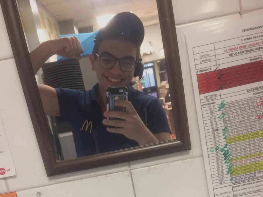 Esteban con el uniforme de McDonald's, reflejado en el espejo del local